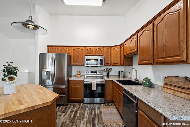 kitchen with dark wood-type flooring, brown cabinets, a sink, and appliances with stainless steel finishes