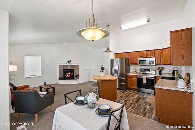 kitchen with stainless steel appliances, open floor plan, brown cabinets, and a sink