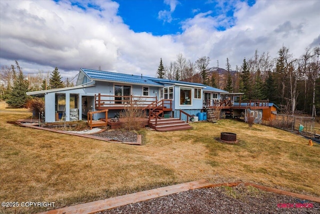 16500 E Smith Rd, Palmer, AK 99645 - back of house featuring an outdoor fire pit, a yard, a deck, and metal roof