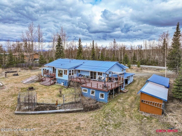 16500 E Smith Rd, Palmer, AK 99645 - rear view of house featuring a deck, a vegetable garden, an outbuilding, a yard, and metal roof