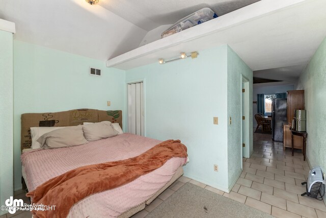 65265 Knob Hill Rd, Anchor Point, AK 99556 - tiled bedroom featuring visible vents, vaulted ceiling, and freestanding refrigerator