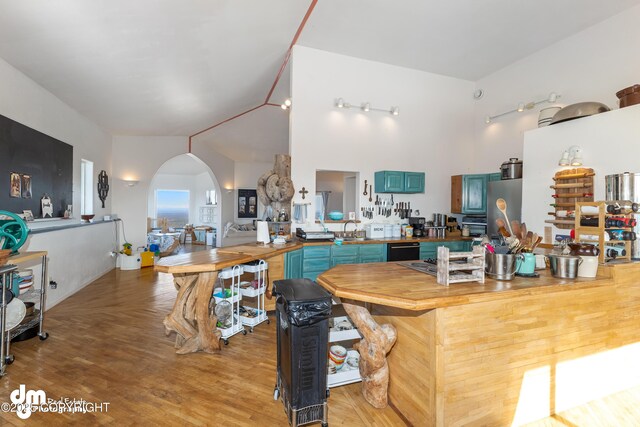 65265 Knob Hill Rd, Anchor Point, AK 99556 - kitchen featuring arched walkways, wooden counters, light wood-style floors, vaulted ceiling, and blue cabinetry