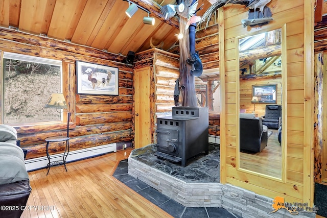 interior details featuring a wood stove, baseboard heating, rustic walls, wooden ceiling, and wood finished floors