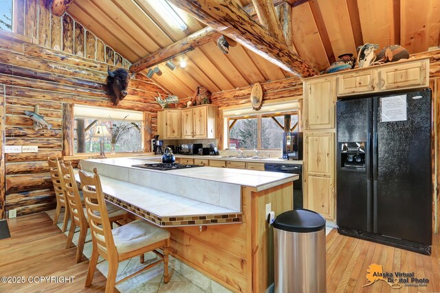 kitchen featuring a wealth of natural light, light wood-style flooring, black appliances, and tile counters