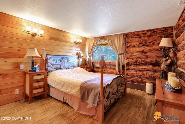 bedroom with wood walls, light wood finished floors, and a textured ceiling