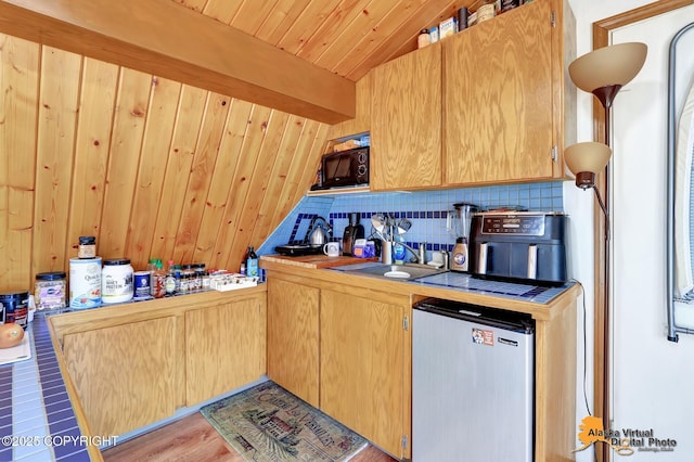 kitchen featuring a sink, wood ceiling, black microwave, fridge, and backsplash