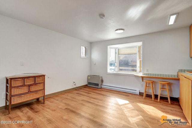interior space with baseboards, light wood-type flooring, and a baseboard heating unit