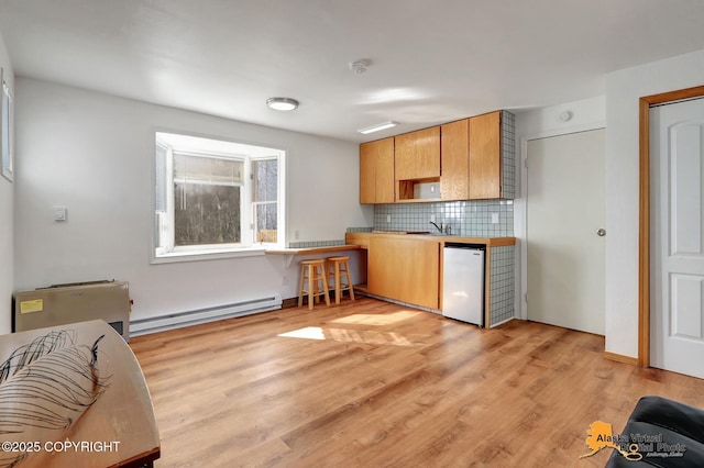 kitchen with dishwashing machine, light wood-type flooring, a baseboard heating unit, a sink, and backsplash