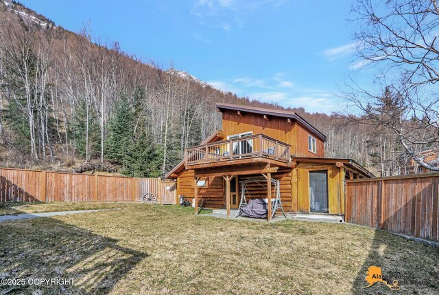 rear view of property with a fenced backyard, a deck, a lawn, and log siding