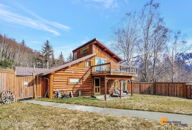 rear view of property featuring a yard, a fenced backyard, a patio, log siding, and a deck