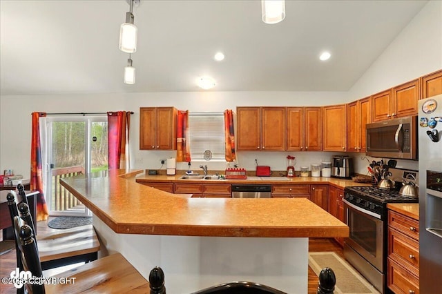3762-3768 S Lansing Rd, Wasilla, AK 99654 - kitchen with stainless steel appliances, a sink, a breakfast bar, brown cabinets, and pendant lighting
