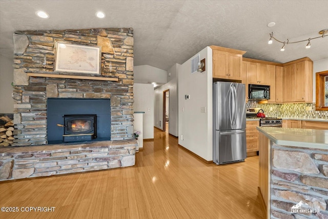 21440 Falling Water Cir, Eagle River, AK 99577 - kitchen featuring appliances with stainless steel finishes, light brown cabinetry, vaulted ceiling, light wood-type flooring, and tasteful backsplash