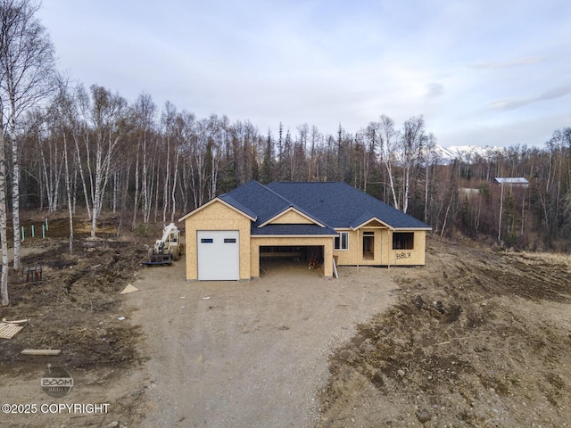 property under construction featuring dirt driveway and a view of trees