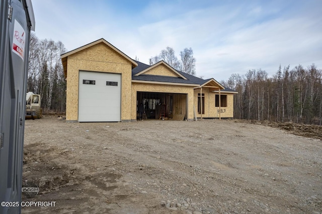 unfinished property featuring dirt driveway and an attached garage