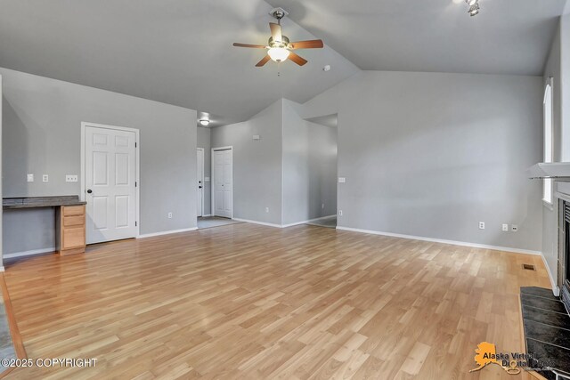unfurnished living room featuring vaulted ceiling, a fireplace, light wood-style floors, visible vents, and ceiling fan