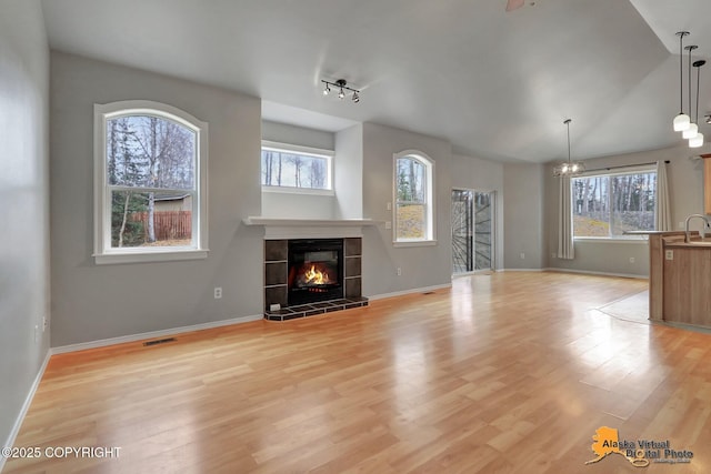 unfurnished living room featuring a tile fireplace, visible vents, baseboards, and a healthy amount of sunlight