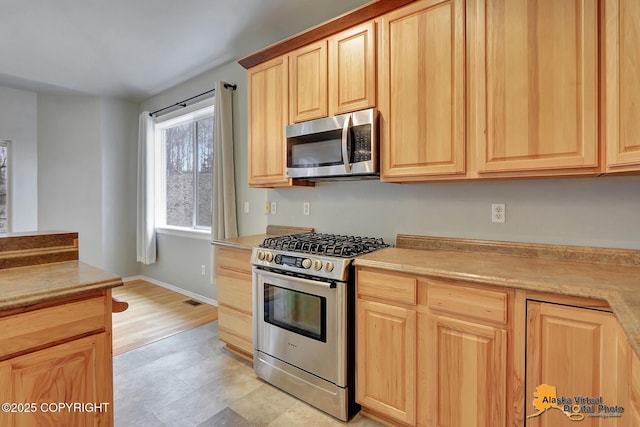 kitchen with light brown cabinetry, visible vents, light countertops, stainless steel appliances, and baseboards