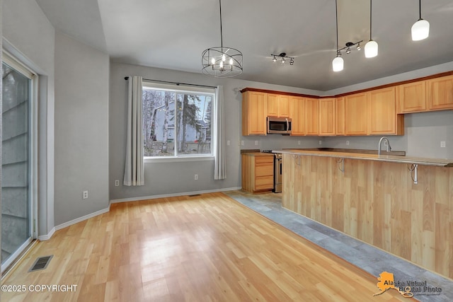 kitchen with light wood-type flooring, light brown cabinetry, visible vents, appliances with stainless steel finishes, and baseboards