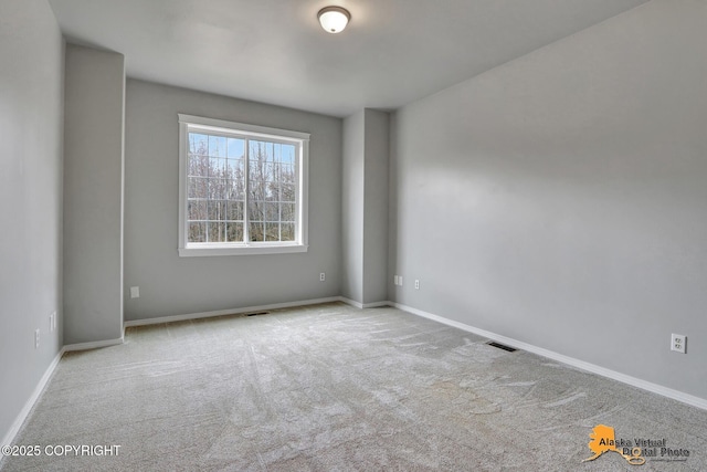 spare room with carpet flooring, baseboards, and visible vents