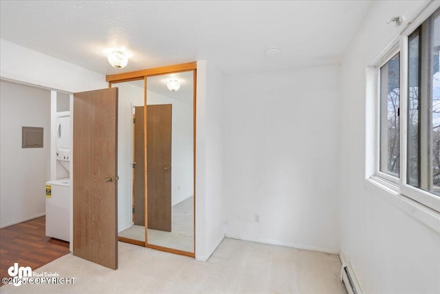 315 Krane Dr # 19, Anchorage, AK 99504 - unfurnished bedroom featuring a baseboard heating unit, stacked washer and clothes dryer, and a closet