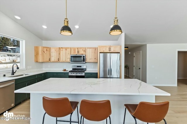 1029 Shelley Ave, Homer, AK 99603 - kitchen featuring stainless steel appliances, light brown cabinetry, light wood-type flooring, a kitchen bar, and decorative light fixtures