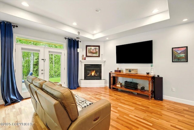 3361 N Inspiration Loop, Wasilla, AK 99654 - living area featuring baseboards, light wood-type flooring, a glass covered fireplace, recessed lighting, and a tray ceiling