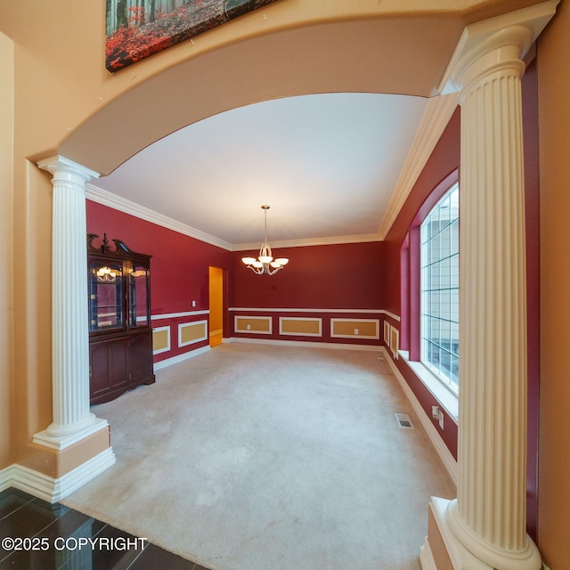 carpeted empty room with an inviting chandelier, ornamental molding, visible vents, ornate columns, and arched walkways
