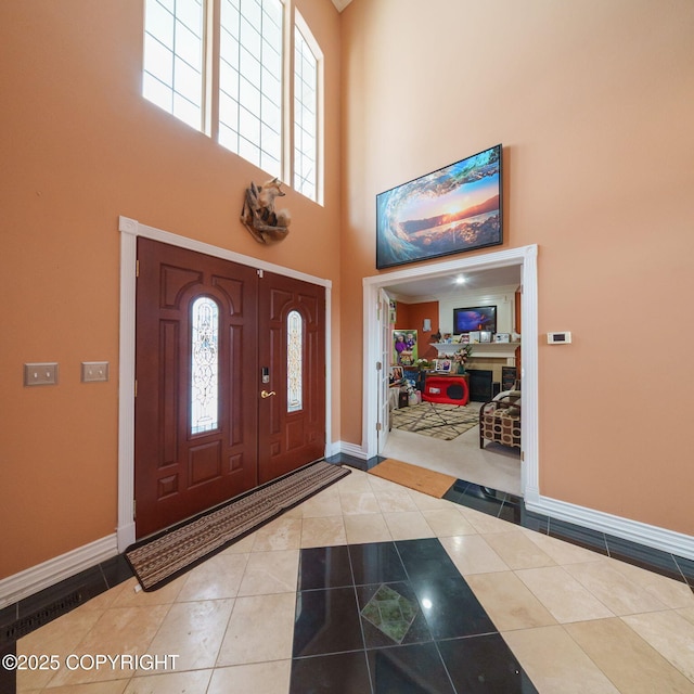 tiled foyer with baseboards and a towering ceiling