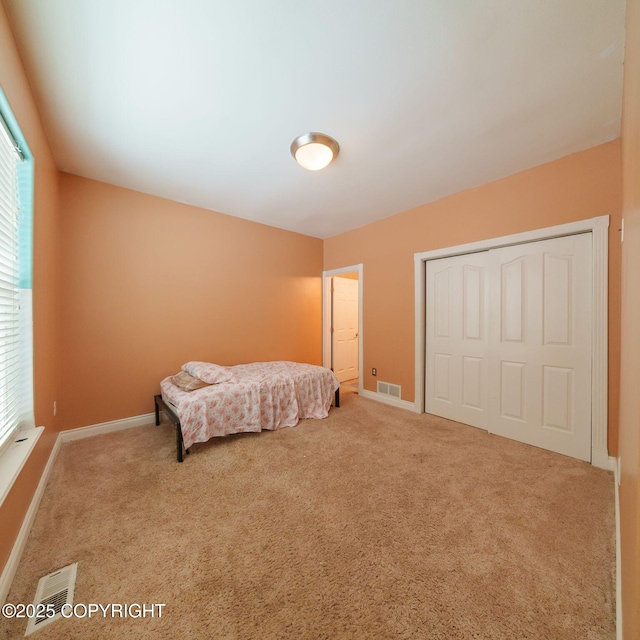 carpeted bedroom featuring a closet, multiple windows, and visible vents