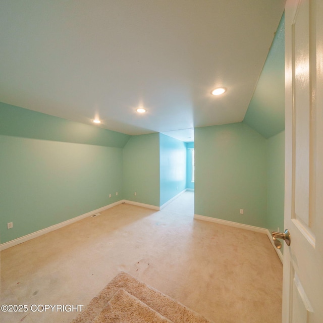 empty room with carpet flooring, baseboards, and vaulted ceiling