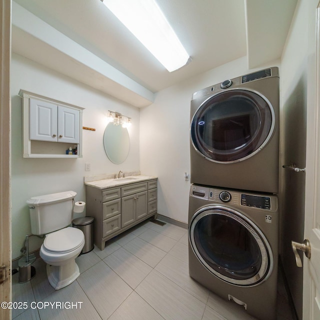 clothes washing area featuring laundry area, light tile patterned floors, a sink, stacked washer and clothes dryer, and baseboards