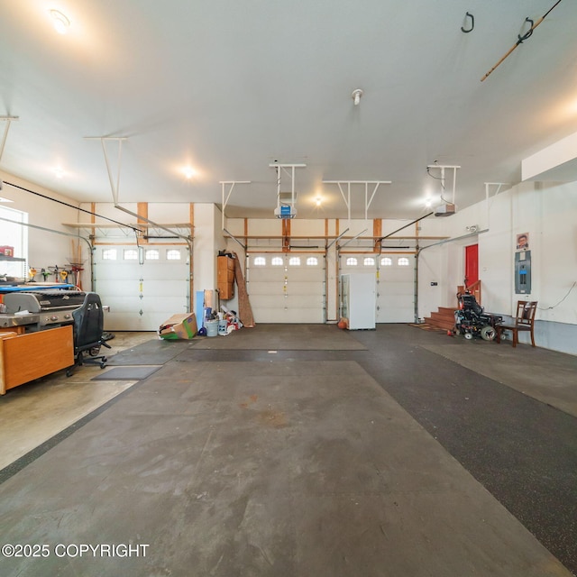 garage featuring freestanding refrigerator, a garage door opener, and electric panel