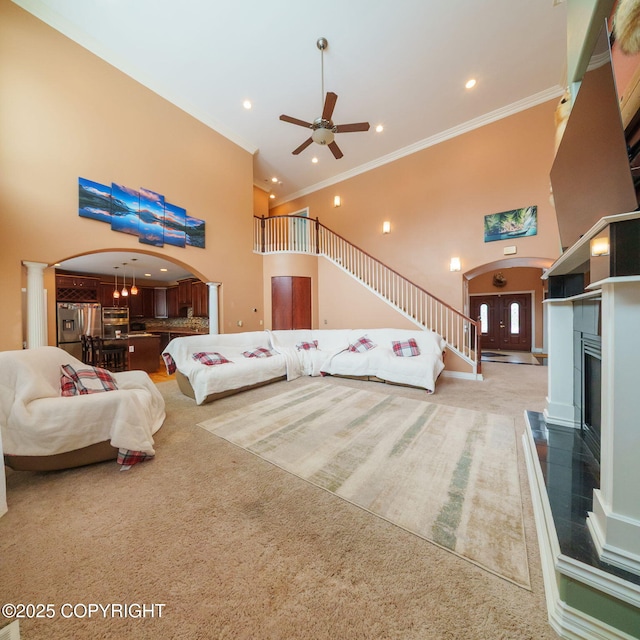 bedroom featuring stainless steel refrigerator with ice dispenser, arched walkways, a high ceiling, carpet flooring, and a tile fireplace