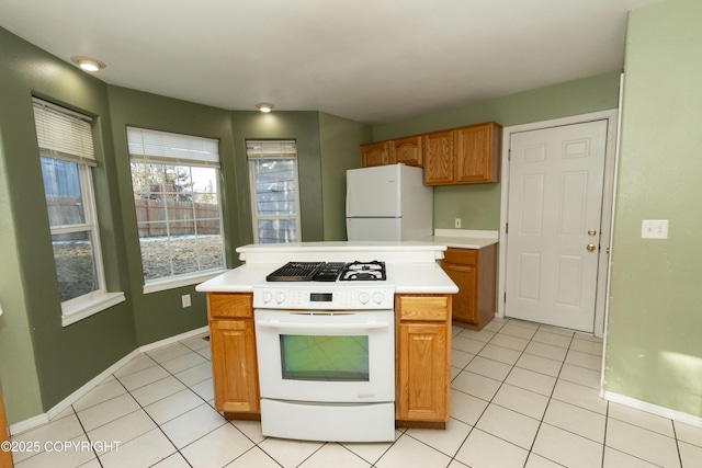10127 Crest View Ln, Eagle River, AK 99577 - kitchen with white appliances, light tile patterned flooring, light countertops, brown cabinets, and baseboards