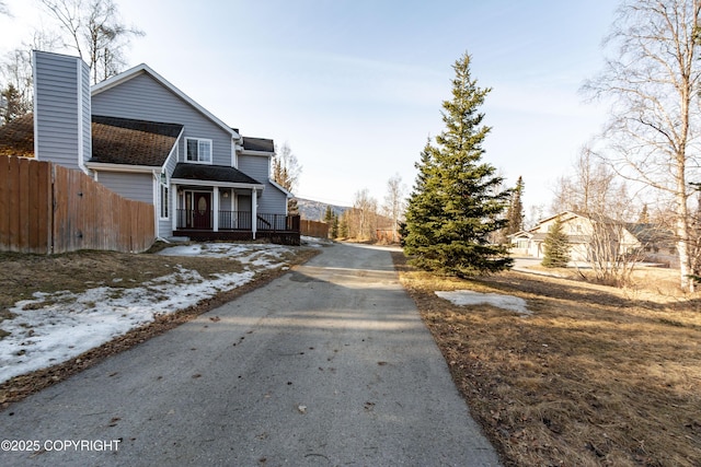 10127 Crest View Ln, Eagle River, AK 99577 - view of front facade with aphalt driveway, a porch, fence, and a chimney