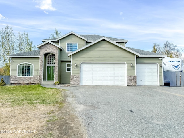 2731 E Tamarak Ave, Wasilla, AK 99654 - view of front facade featuring a garage, stone siding, driveway, and a shingled roof