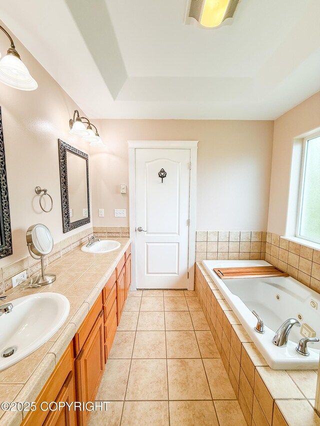 2731 E Tamarak Ave, Wasilla, AK 99654 - full bathroom featuring a tray ceiling, a jetted tub, double vanity, and tile patterned flooring