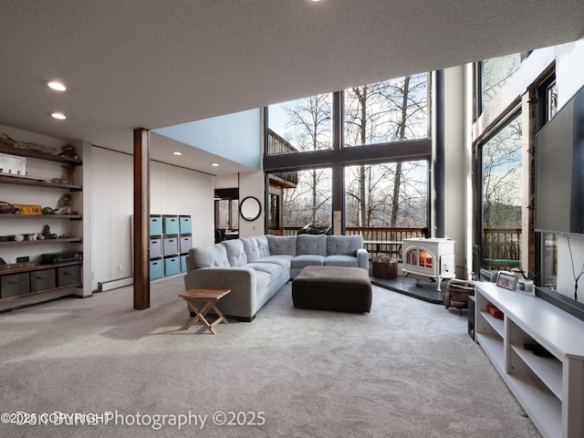 11730 Broadwater Dr, Eagle River, AK 99577 - carpeted living room with recessed lighting, expansive windows, a wood stove, plenty of natural light, and a baseboard heating unit