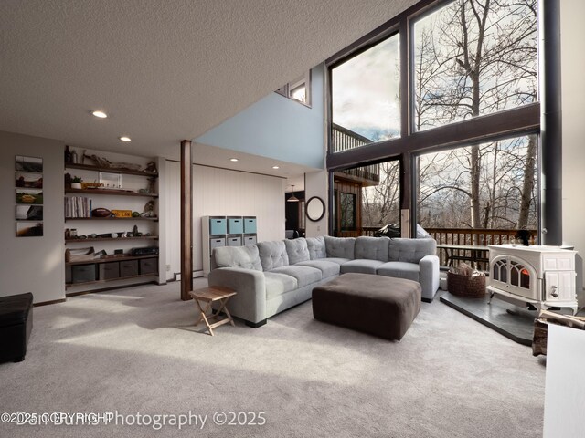 11730 Broadwater Dr, Eagle River, AK 99577 - carpeted living area featuring a wood stove, plenty of natural light, recessed lighting, a towering ceiling, and a textured ceiling