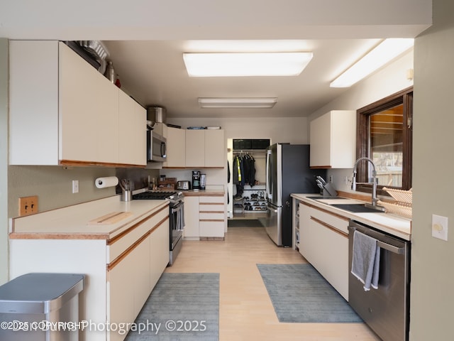 11730 Broadwater Dr, Eagle River, AK 99577 - kitchen featuring stainless steel appliances, a sink, white cabinetry, light wood finished floors, and light countertops