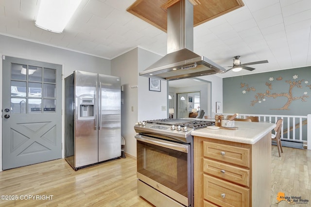 4303 E 3rd Ave, Anchorage, AK 99508 - kitchen with light countertops, ceiling fan, appliances with stainless steel finishes, island range hood, and light wood-style flooring