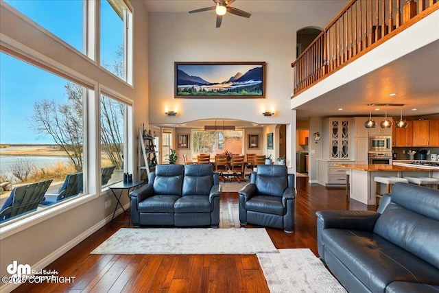 47366 Winridge Ave, Kenai, AK 99611 - living room featuring baseboards, dark wood-style flooring, a towering ceiling, a ceiling fan, and a water view
