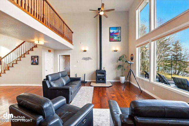 47366 Winridge Ave, Kenai, AK 99611 - living area featuring a wood stove, a towering ceiling, stairs, a ceiling fan, and wood-type flooring