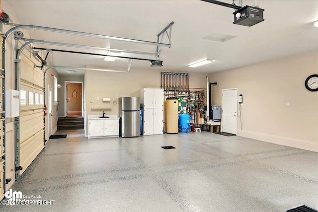 47366 Winridge Ave, Kenai, AK 99611 - garage with freestanding refrigerator, a garage door opener, water heater, and a sink