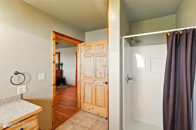 22045 Becharof Cir, Kasilof, AK 99610 - bathroom featuring a shower stall, a textured wall, tile patterned flooring, and vanity