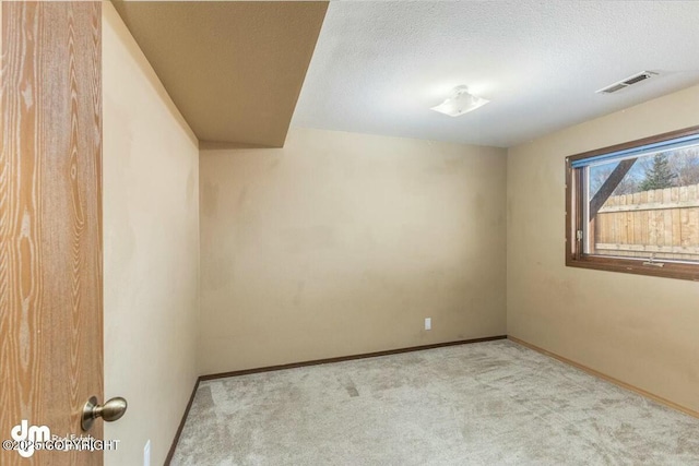 carpeted empty room with a textured ceiling, visible vents, and baseboards