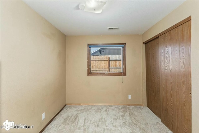 unfurnished bedroom with baseboards, carpet floors, visible vents, and a closet