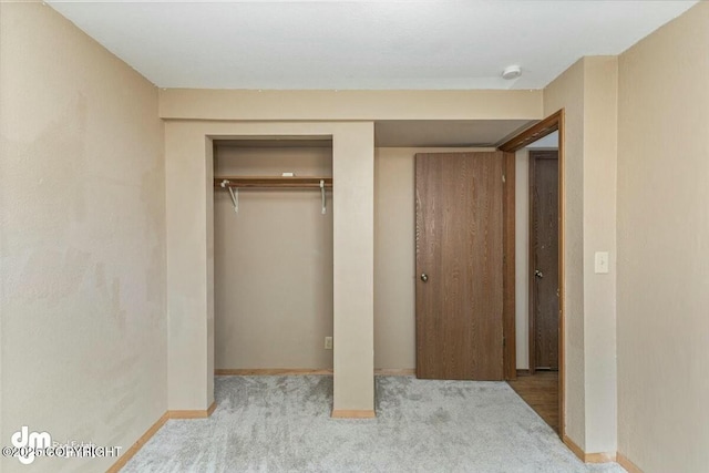 unfurnished bedroom featuring baseboards, carpet flooring, and a closet