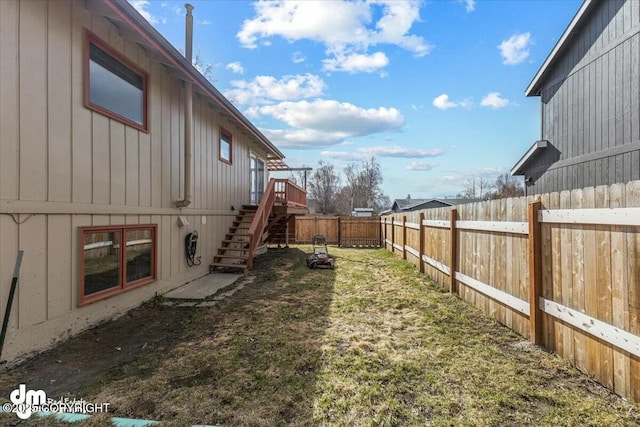 view of yard with a fenced backyard, a deck, and stairs