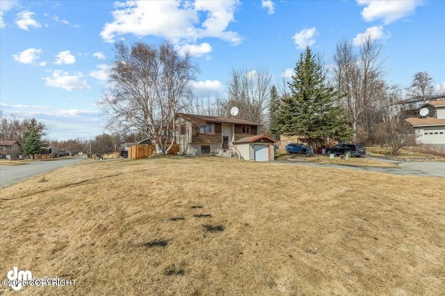 raised ranch with a front lawn and a detached garage
